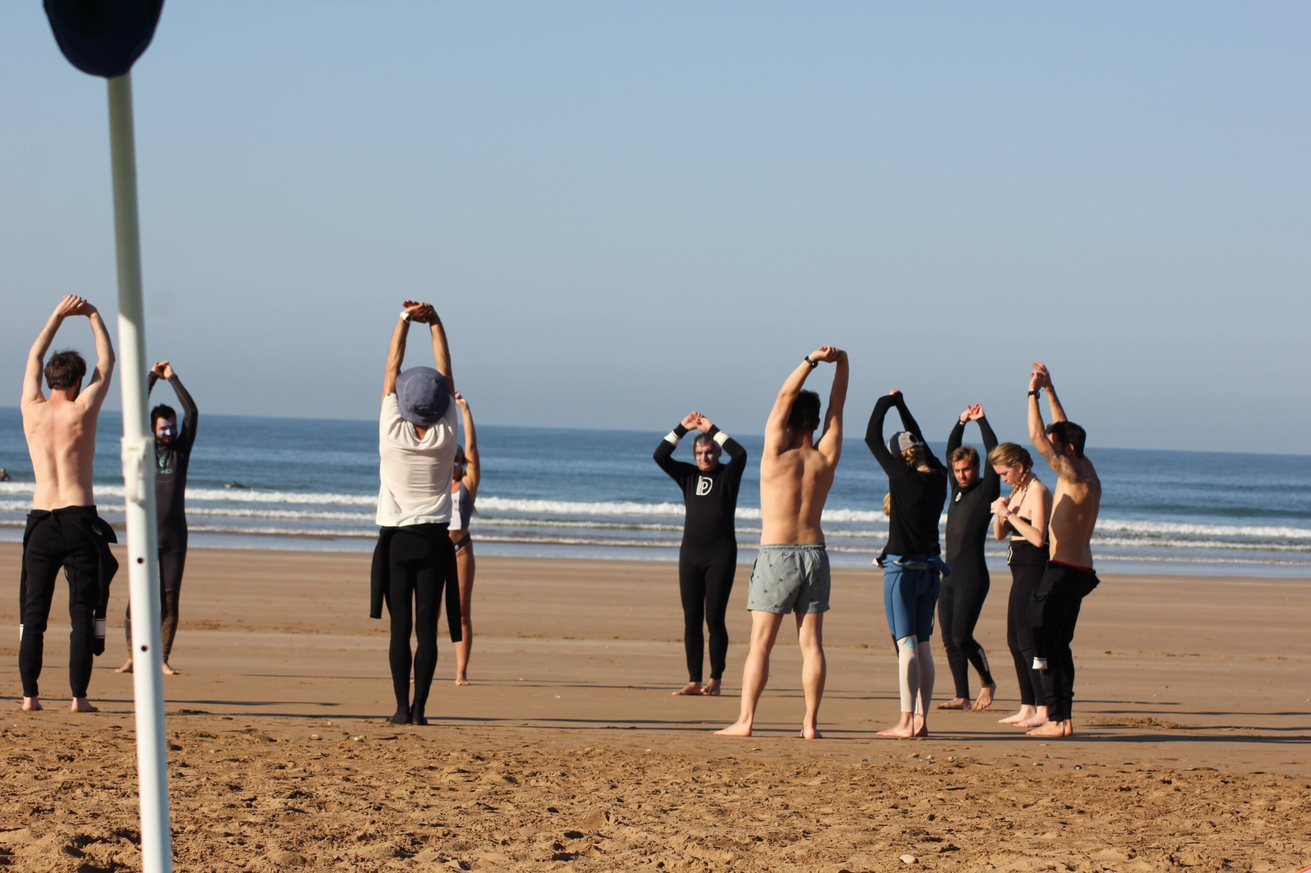 Surfer practising pop-up technique on a yoga mat during a surf & yoga session on the beach in Taghazout Morocco